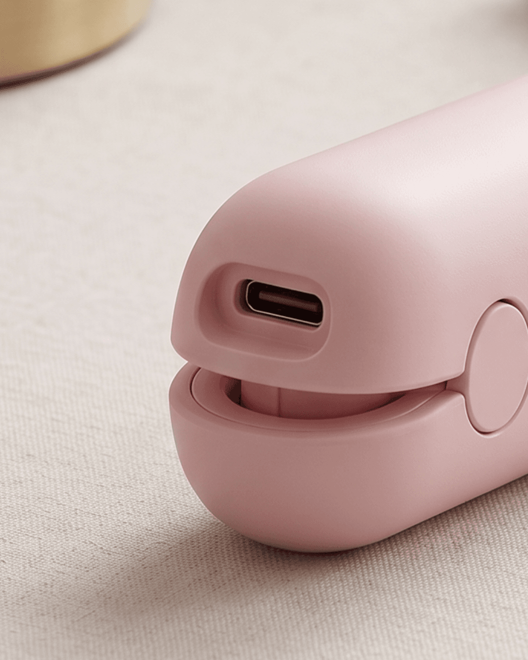 Close-up of a pink electronic device with a USB-C charging port on a textured surface.